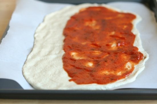 Pizza sauce on half of the rolled out pizza dough