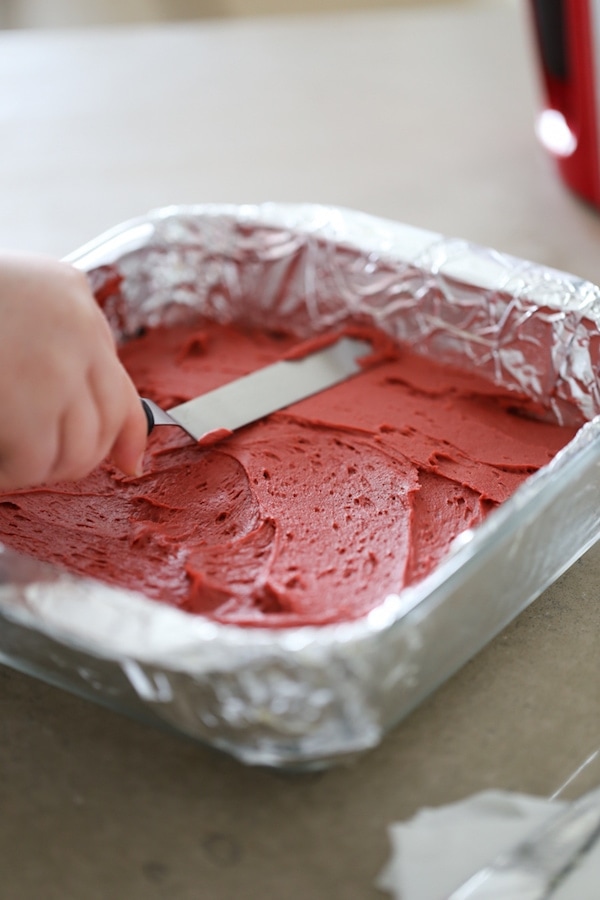 Smoothing out red velvet mixture on top of chocolate mixture