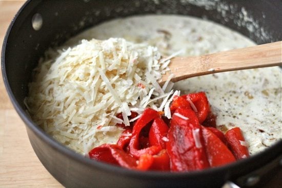 Adding cheese and red peppers to the sauce