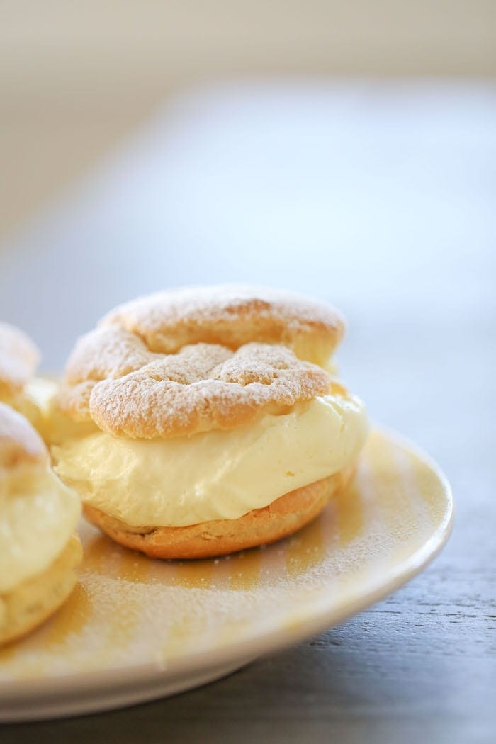 lemon cream puffs on a white plate dusted with powdered sugar
