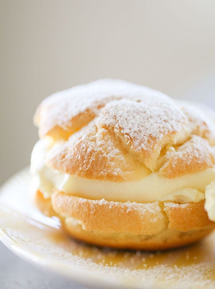 lemon cream puff on a white plate dusted with powdered sugar