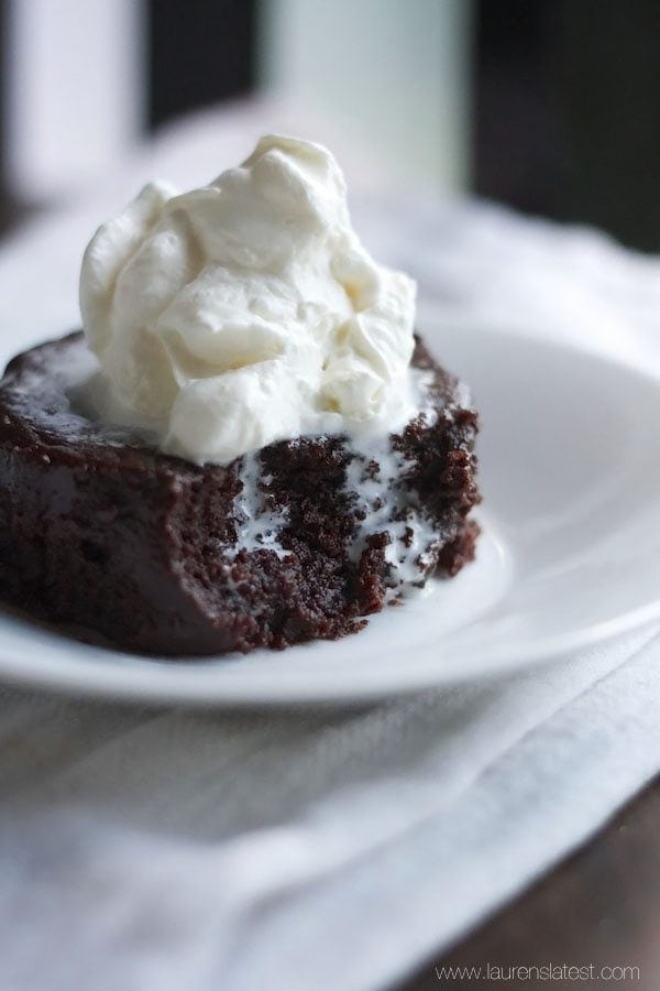 Mug Brownie on a white plate with whipped cream on top. A couple of forkfuls have been eaten from the brownie.