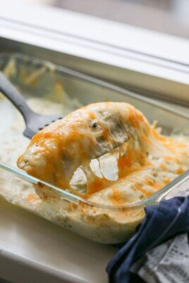 scooping a chicken enchilada out of the baking dish