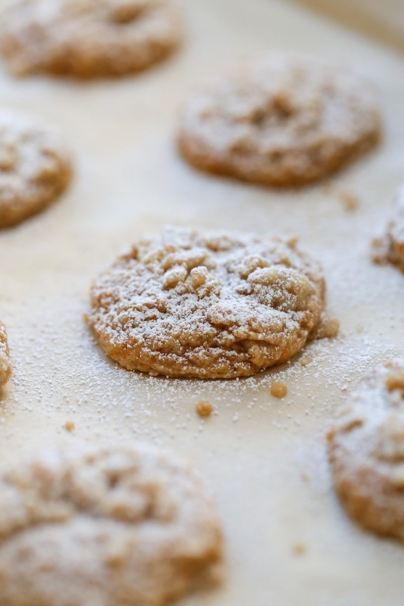 sweet potato cookies on a parchment paper lined baking sheet dusted in powdered sugar