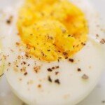close up of a sliced hard boiled egg with salt and pepper