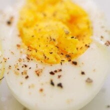 close up of a sliced hard boiled egg with salt and pepper