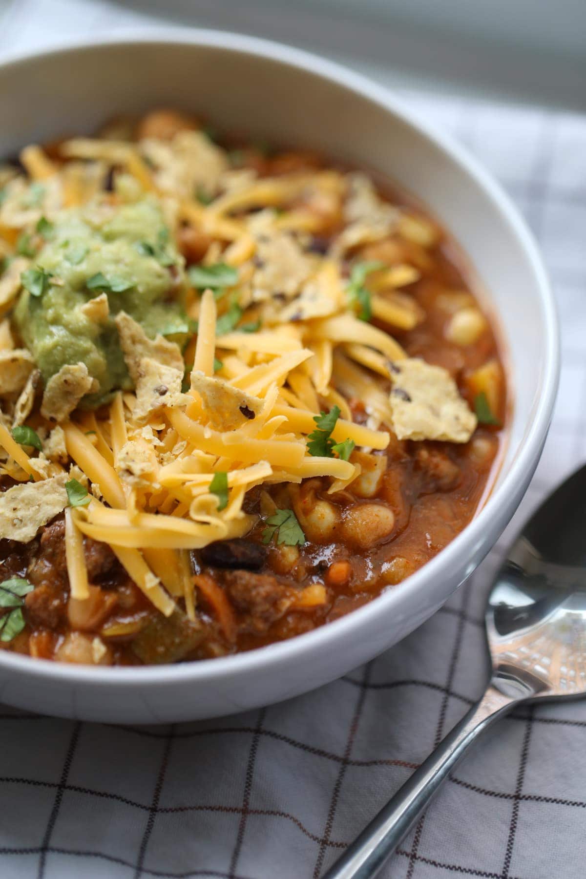 Close up of Taco Soup in a white bowl with toppings