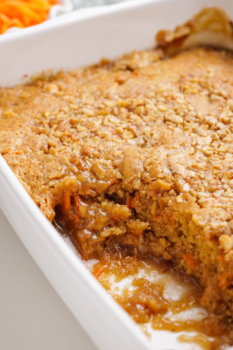 carrot cake cobbler in baking dish with a piece cut out