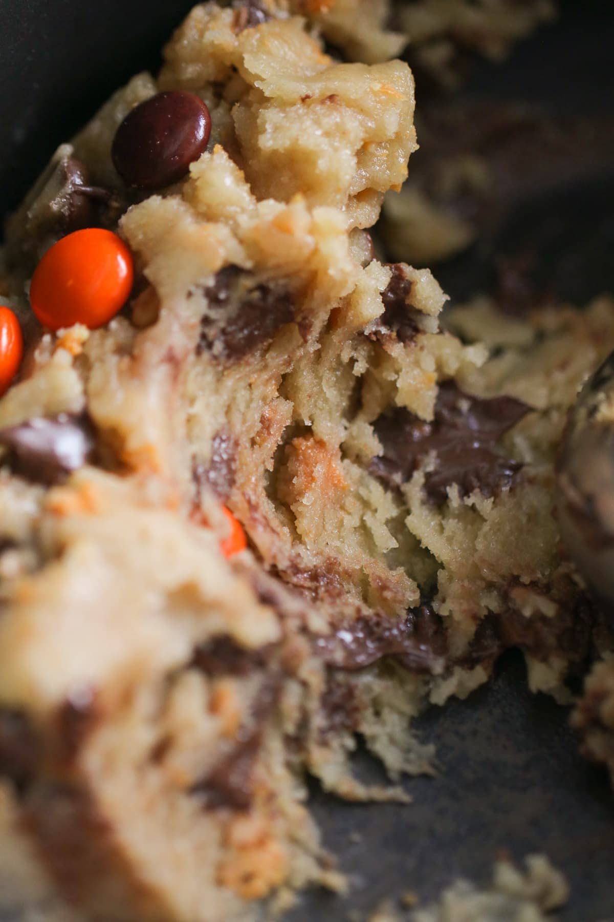 close up shot of cookie dough laced with butterfinger chunks and reeses pieces