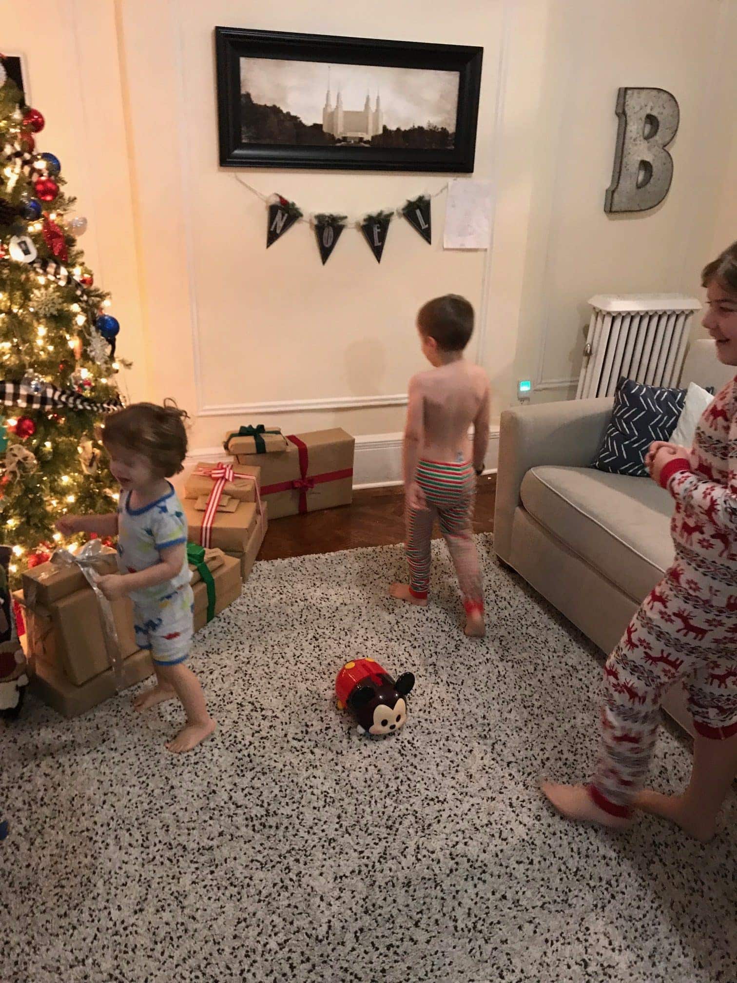 The kids walking towards the Christmas tree with presents