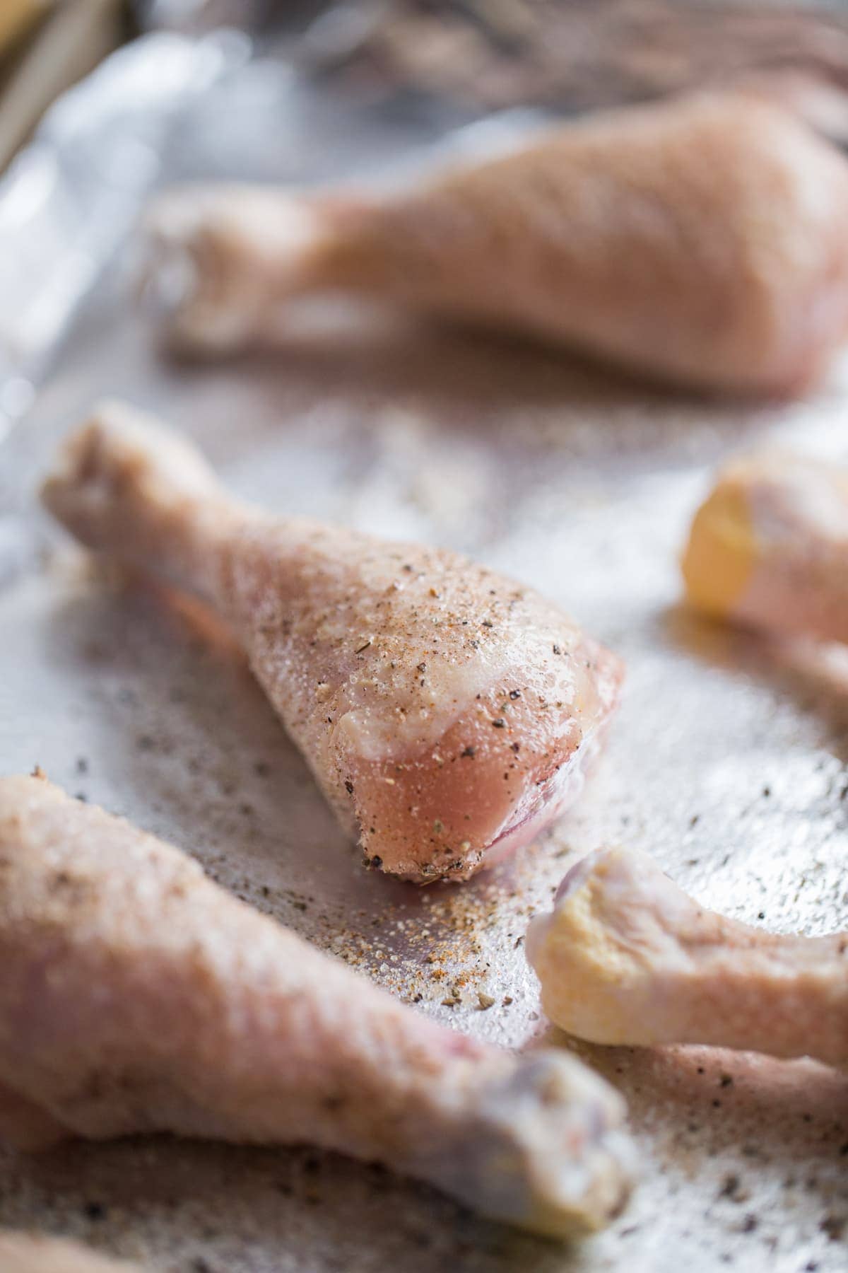 chicken drumsticks on baking sheet with seasoning