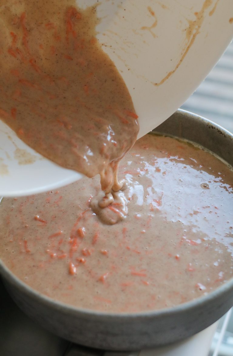carrot cake batter being poured into a cake pan
