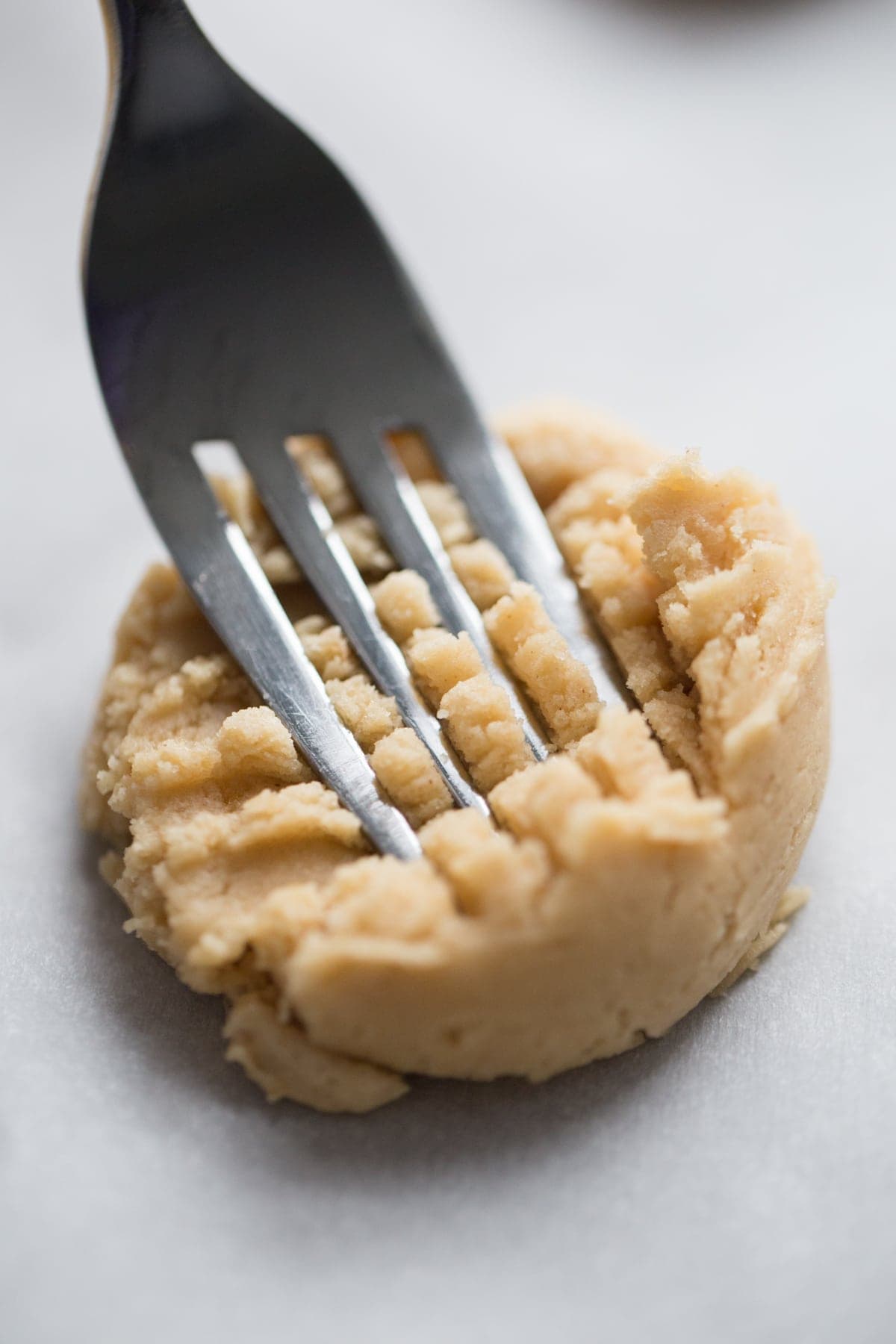 fork pressing down into a ball of peanut butter cookie dough