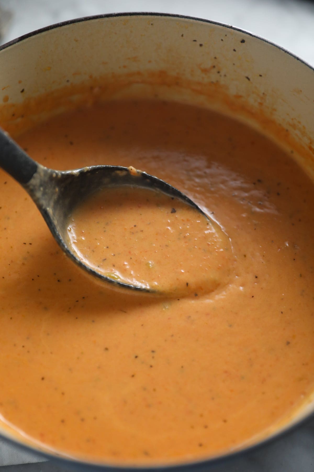 stirring tomato bisque in a pot