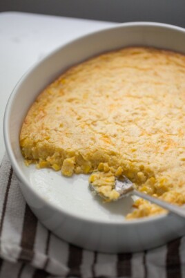 partial corn casserole in a round pan with a serving spoon