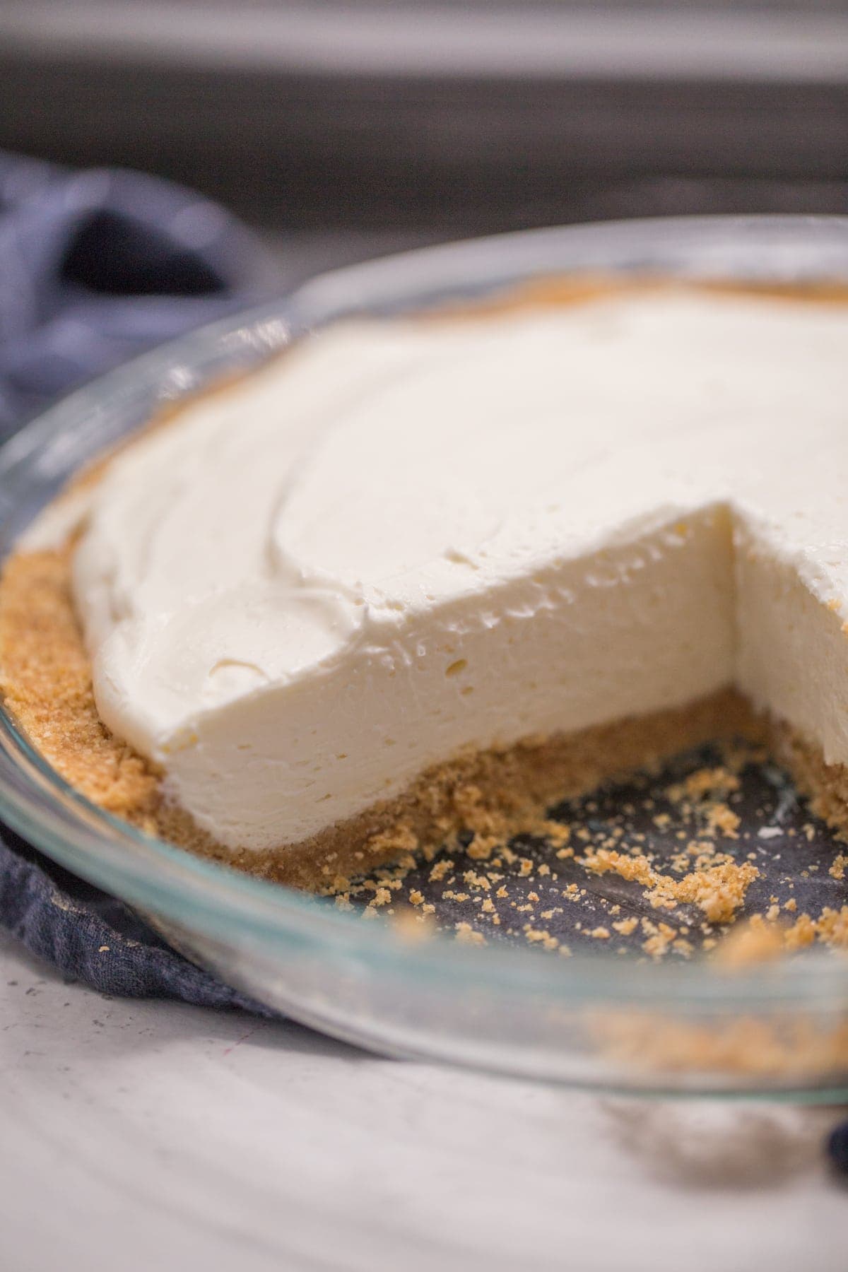 plain no bake cheesecake with slice removed in a glass pie tin