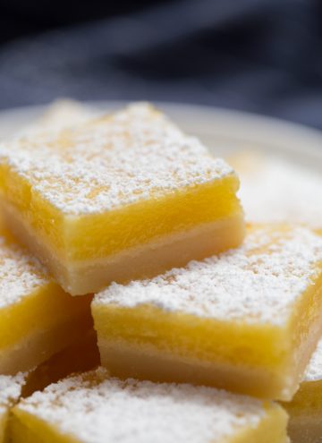 lemon bars stacked on top of each other on a white plate