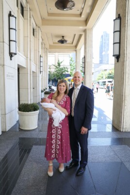Parents holding their baby in front of a building