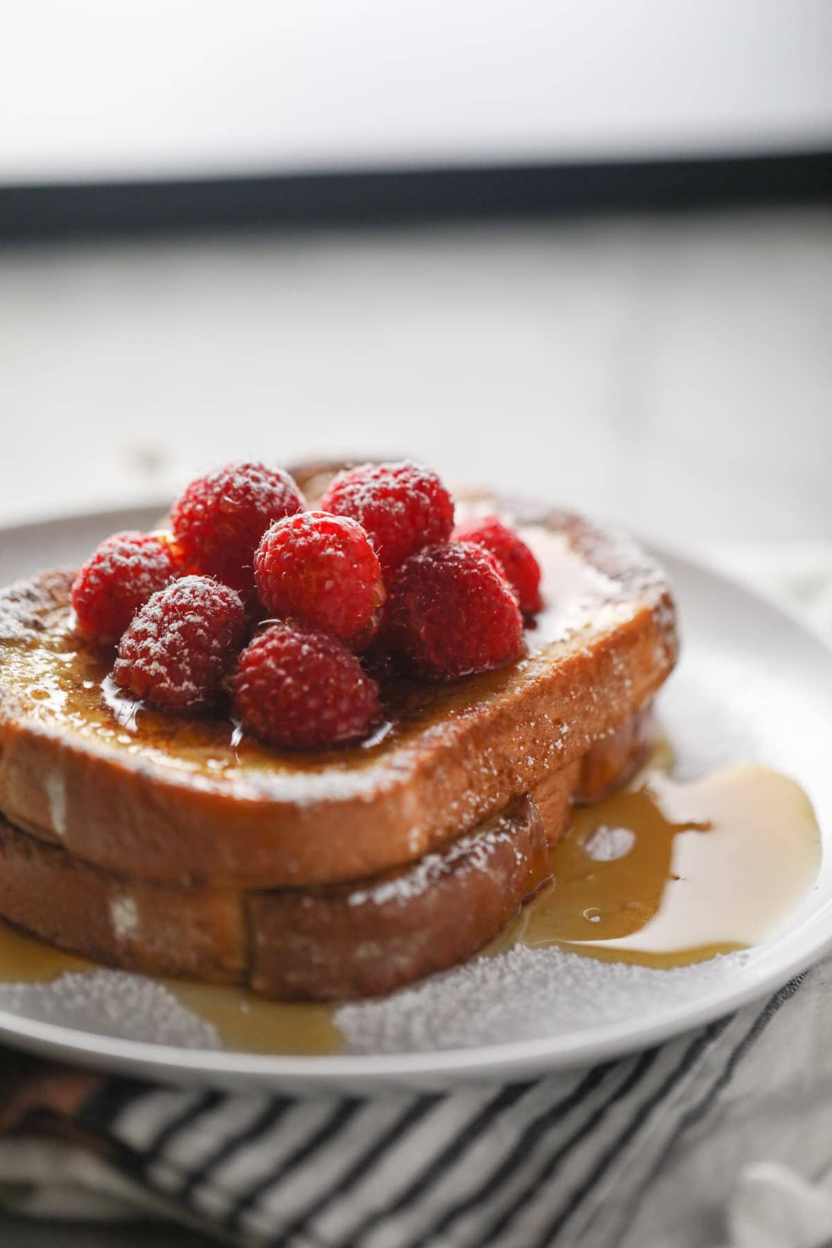 french toast with berried and maple syrup all on a white plate