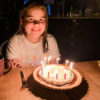Brooke sitting at a table with a birthday cake with lit candles