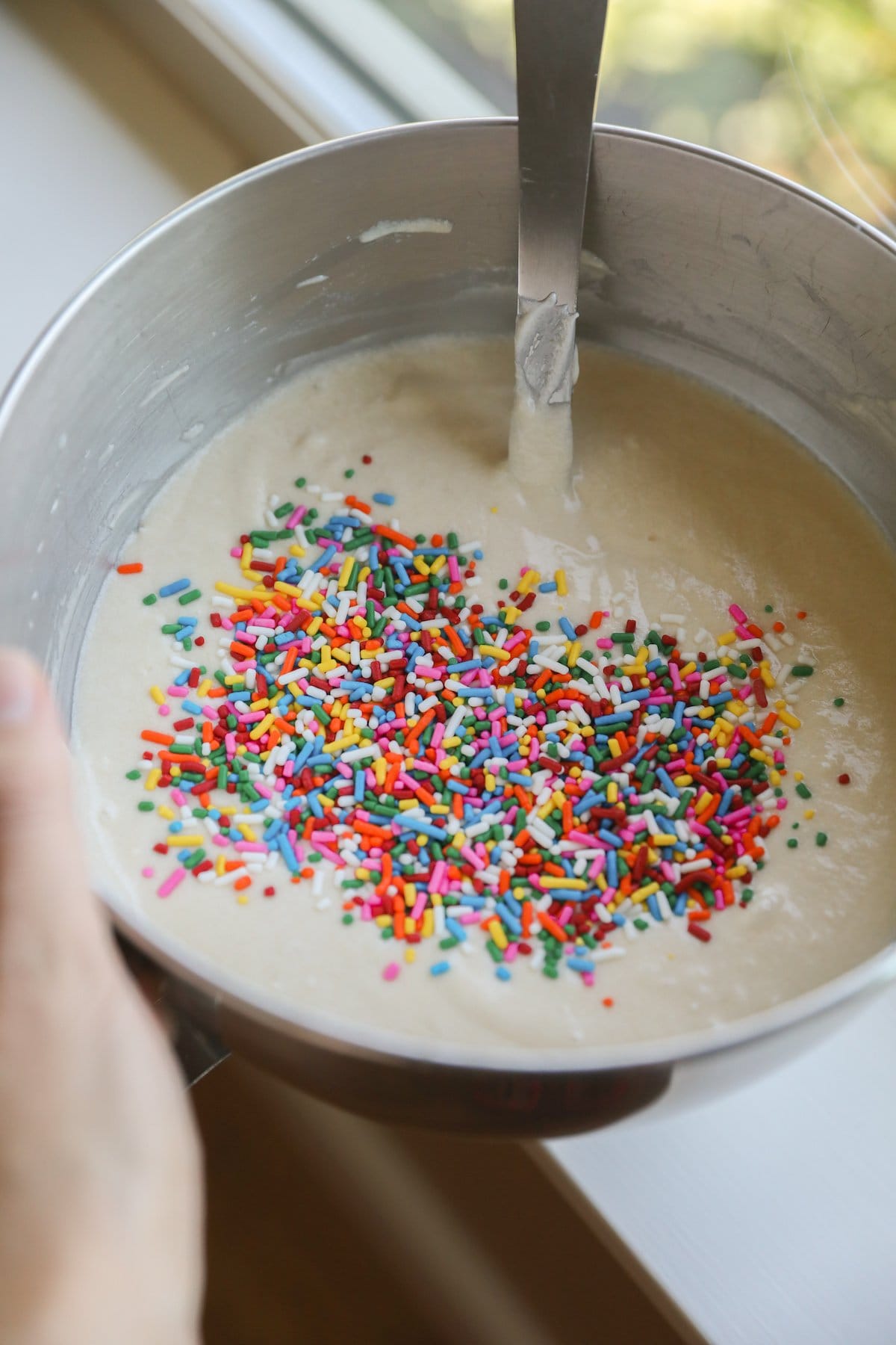 cake batter in bowl with sprinkles on top not folded in yet