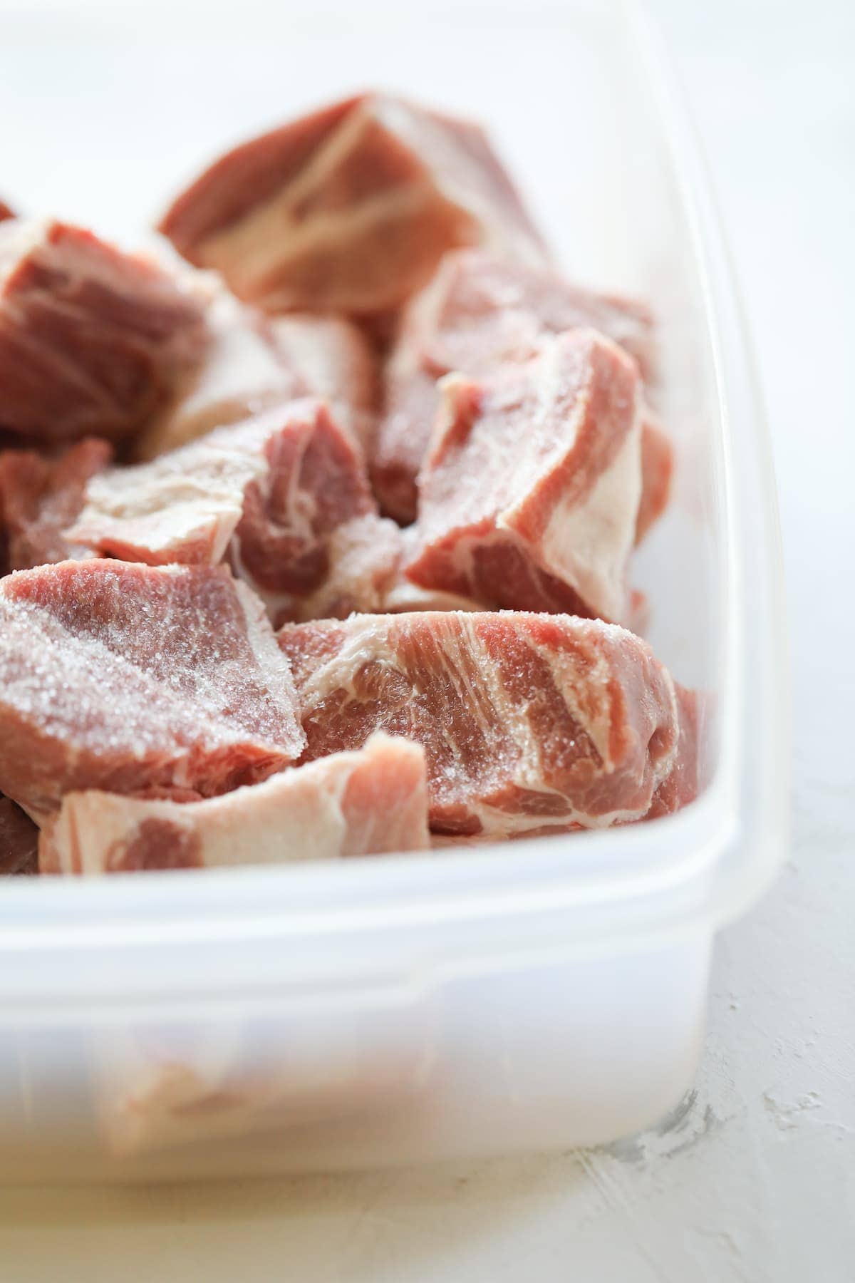 chunks of pork shoulder in plastic container