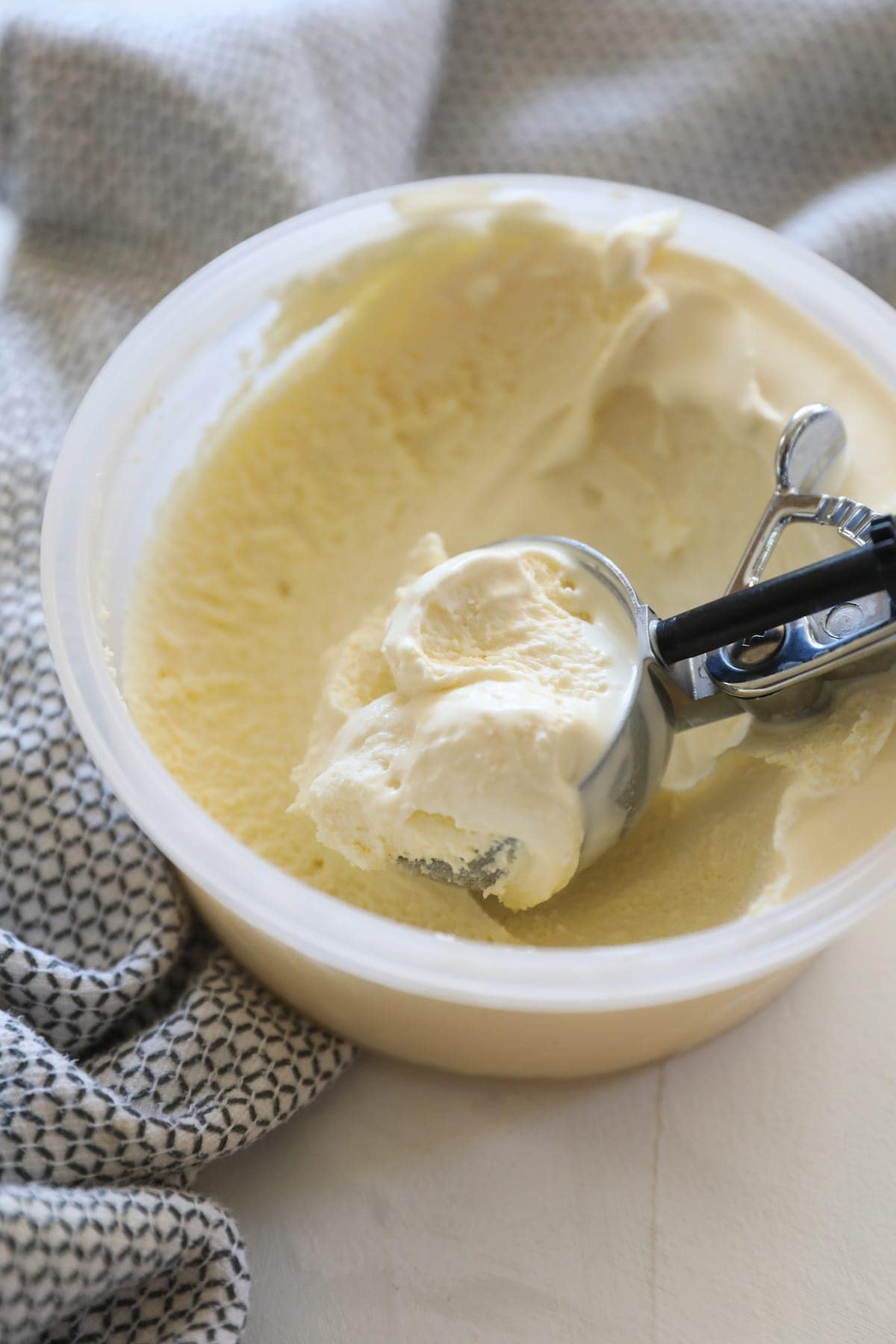 scoop of vanilla ice cream sitting in container of ice cream