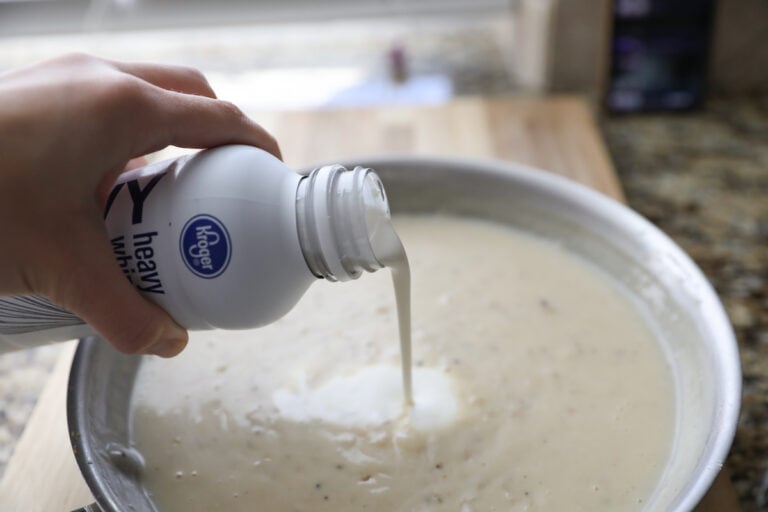 pouring heavy cream into white sauce
