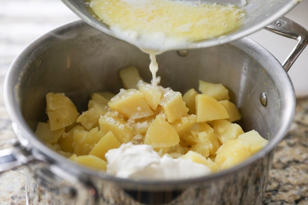pouring butter, milk and garlic into poatoes