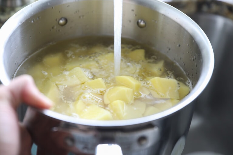 adding water to cut potatoes in pot