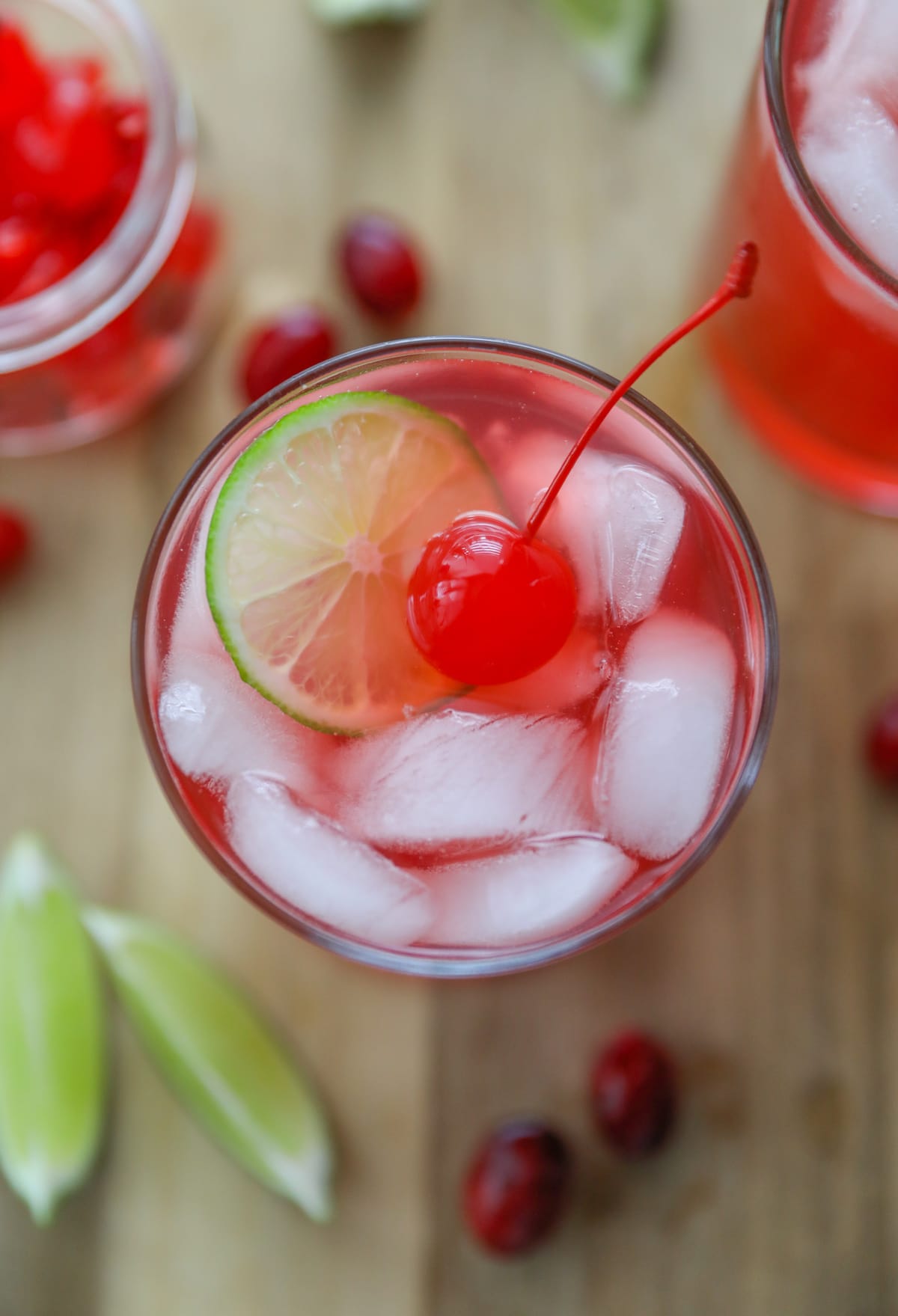 glass filled with a holiday mocktail, with ice, slice of lime and cherry