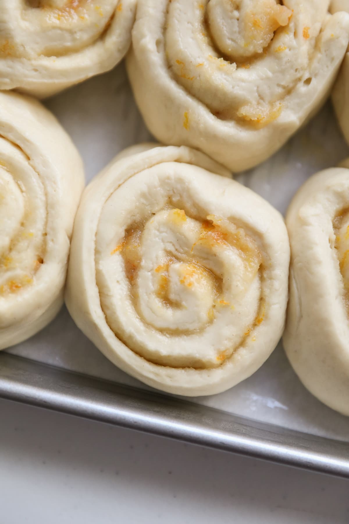 risen orange rolls in baking sheet