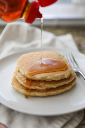 pouring syrup on oatmeal pancakes