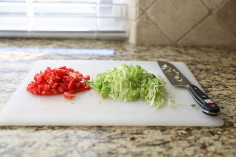 chopped tomatoes and lettuce on cutting board