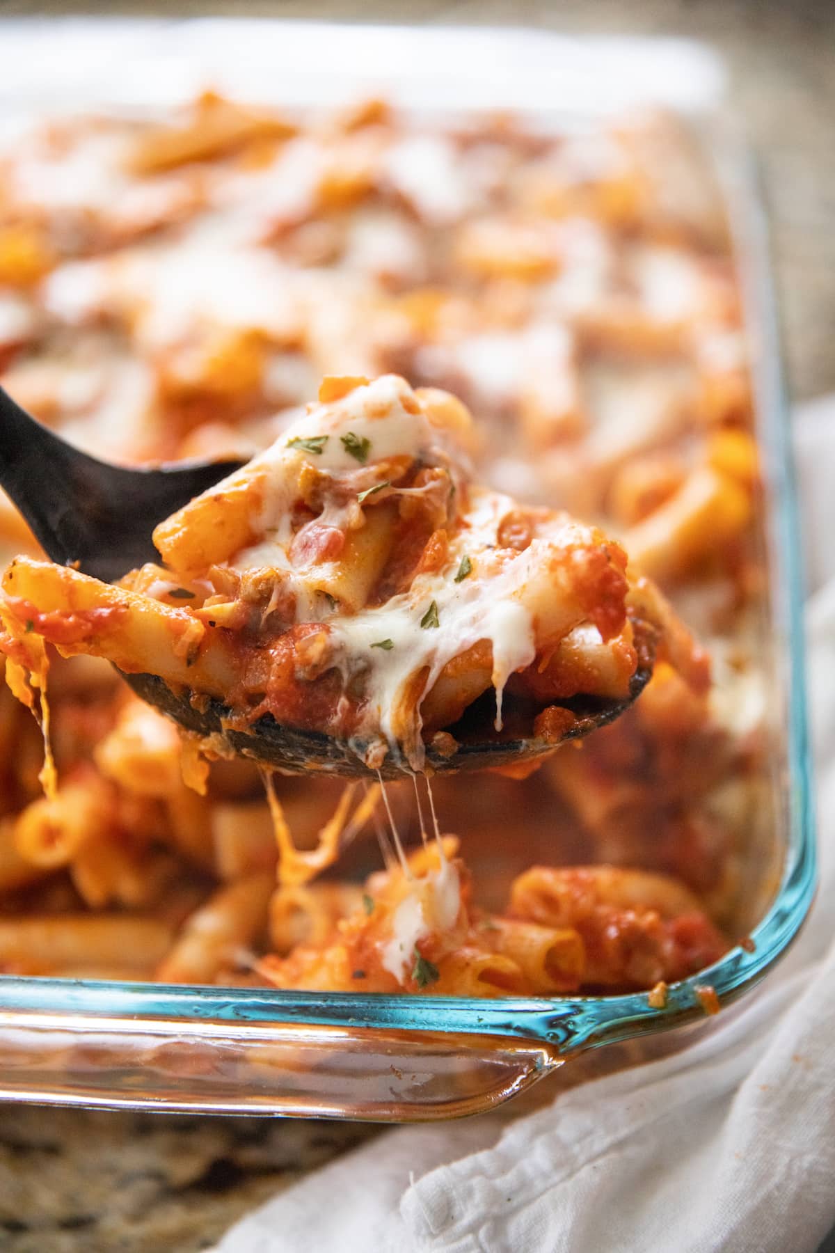 scooping baked ziti out of pan