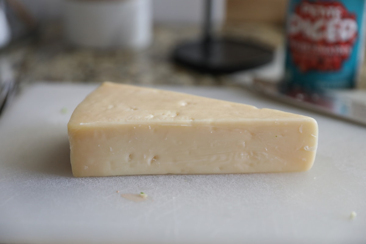 block of parmesan cheese on cutting board