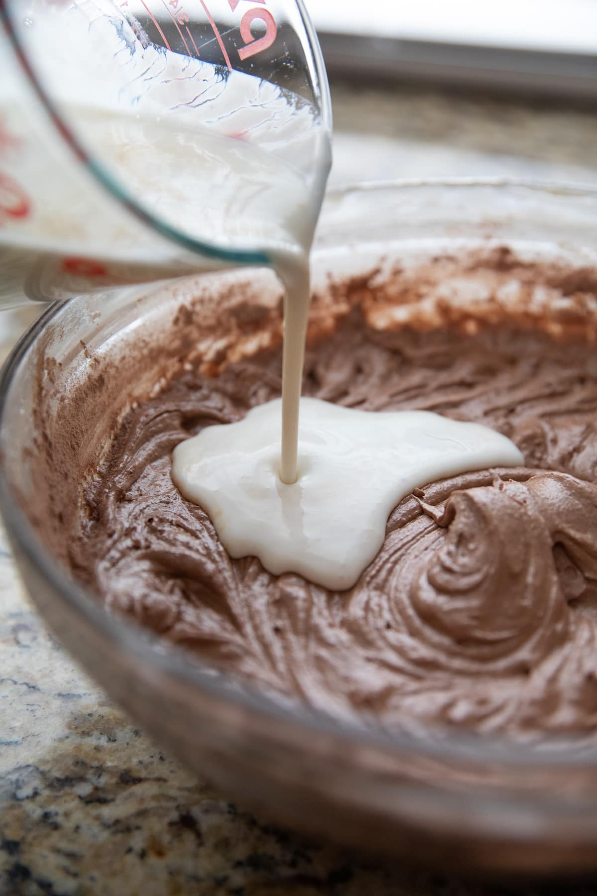 pouring in buttermilk into chocolate cake batter