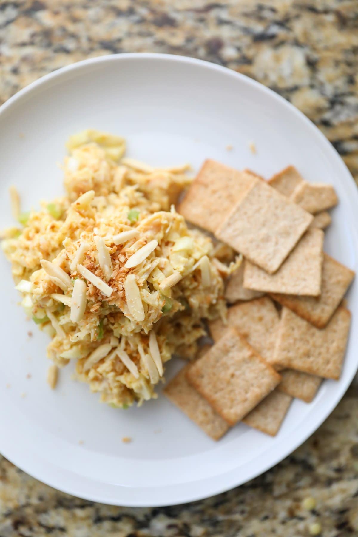 curry chicken salad with crackers on a white plate