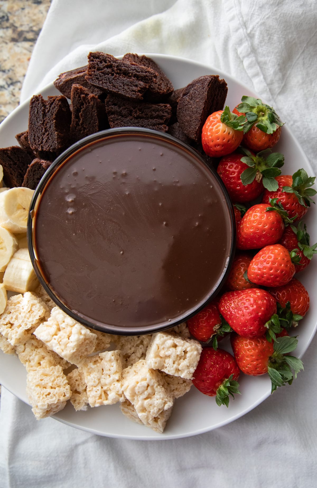 platter of dipping chocolate with strawberries, brownies, banana and rice krispie treats