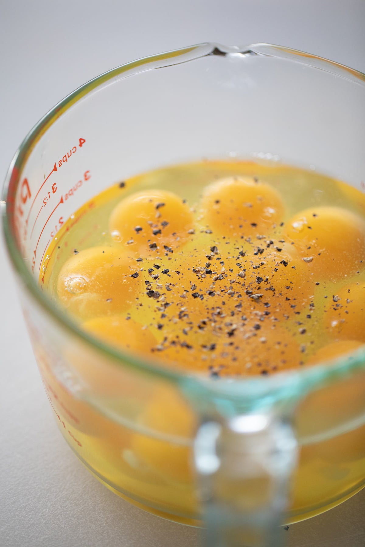 cracked eggs in liquid measuring cup salt & pepper