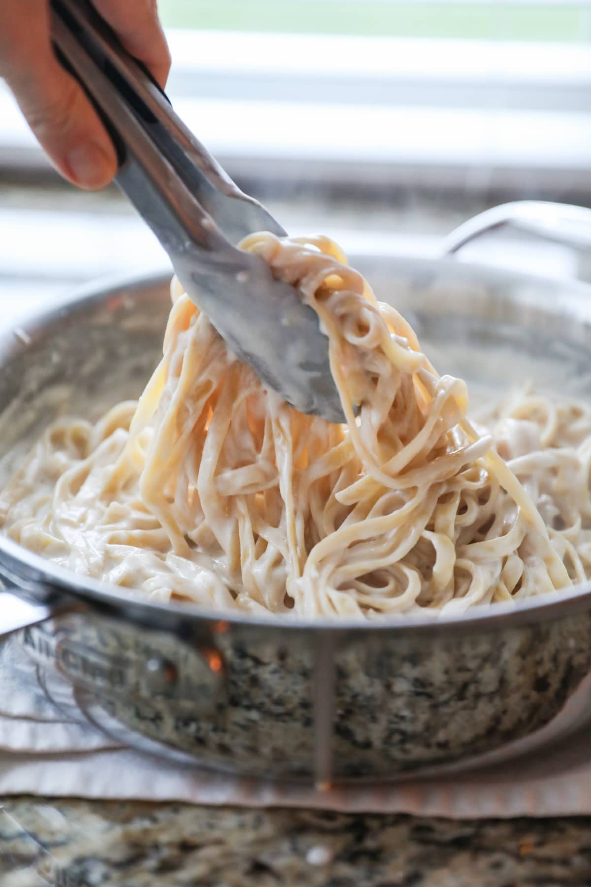 tossing sauce with fettuccine
