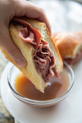 dipping french dip sandwich in au jus