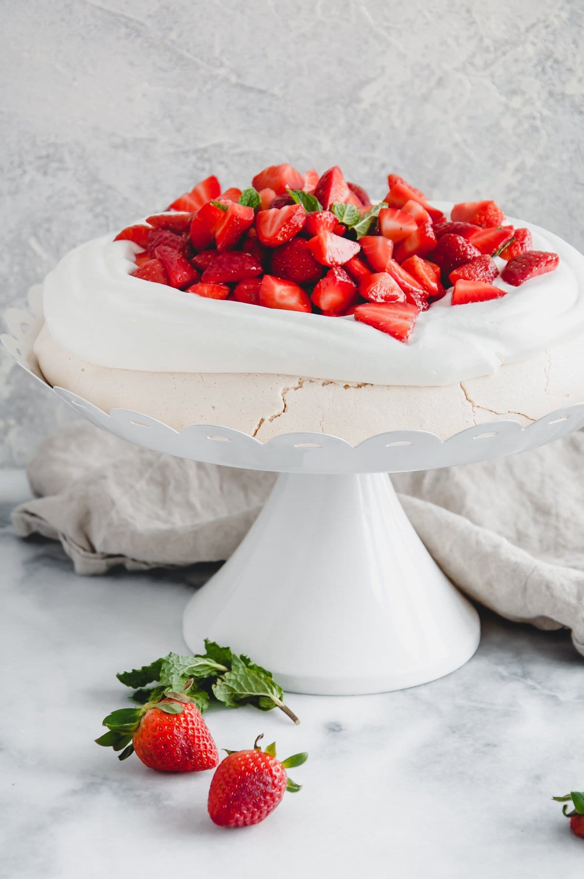 strawberry pavlova on a white cake stand