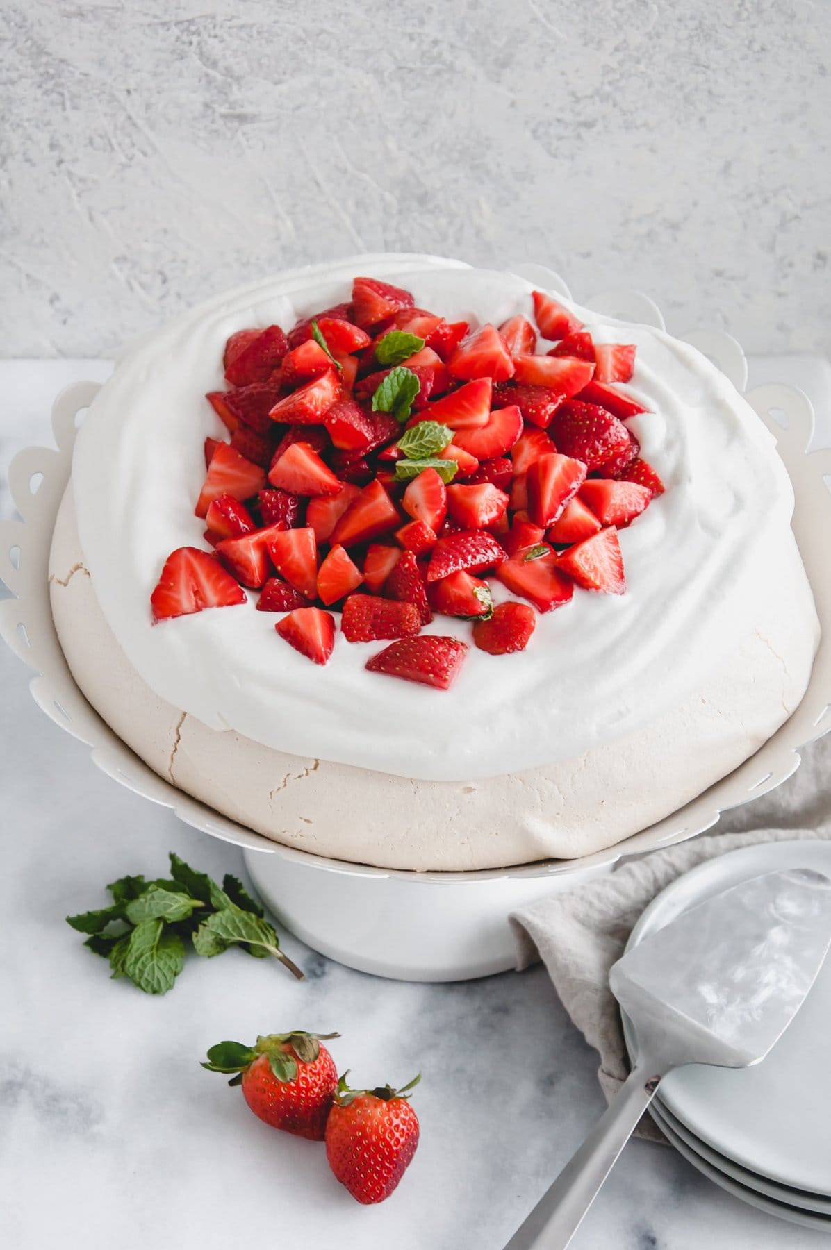 three quarters view of strawberry pavlova on a white cake stand