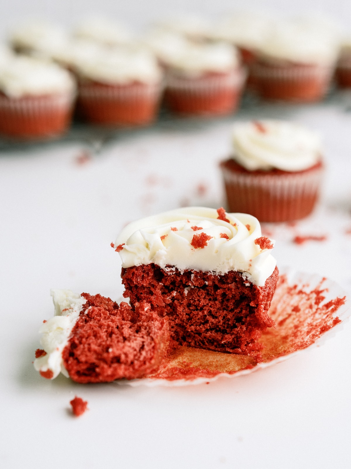 red velvet cupcake unwrapped and cut in half with cupcakes in the background