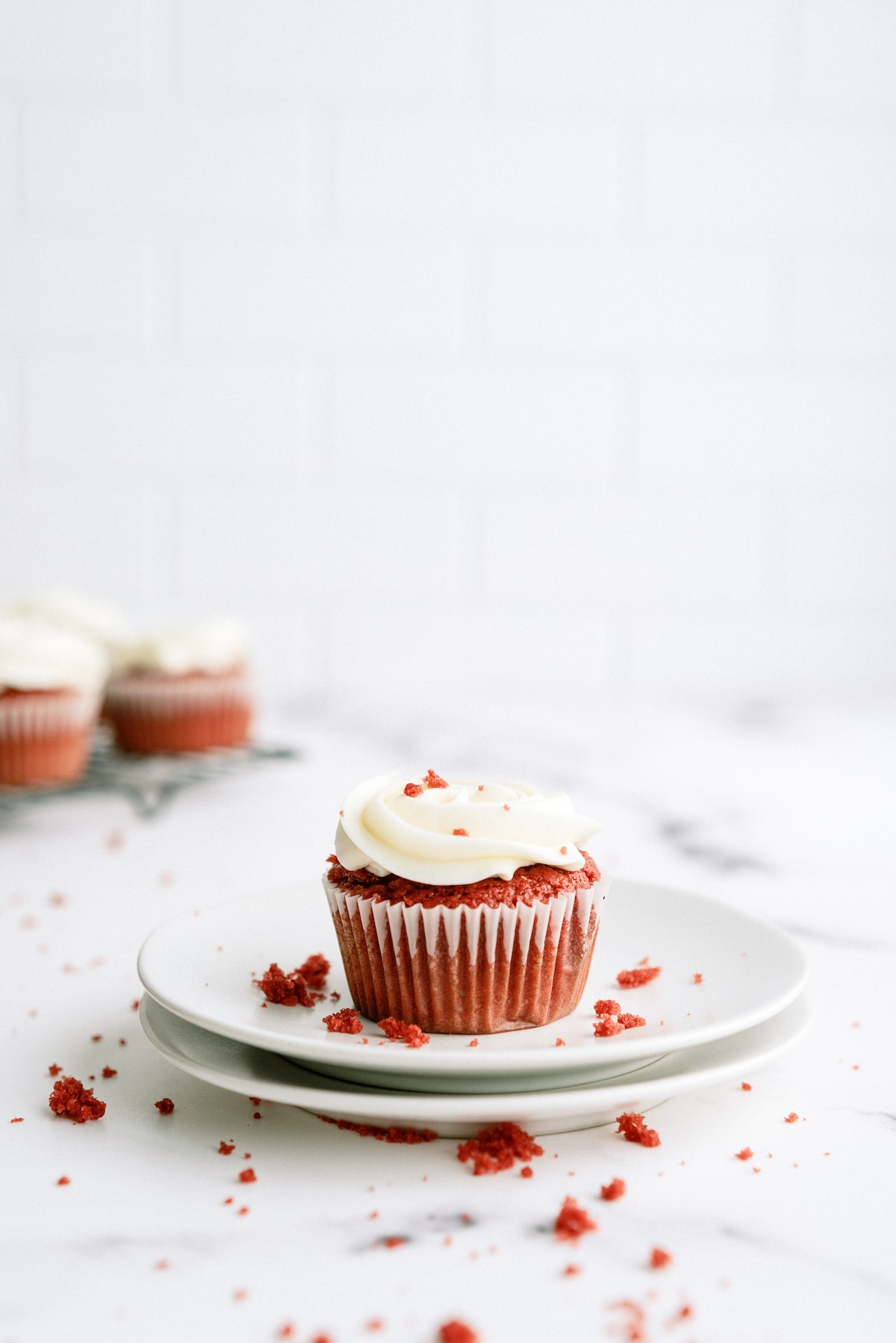 red velvet cupcake on a white plate with some cupcakes in the background