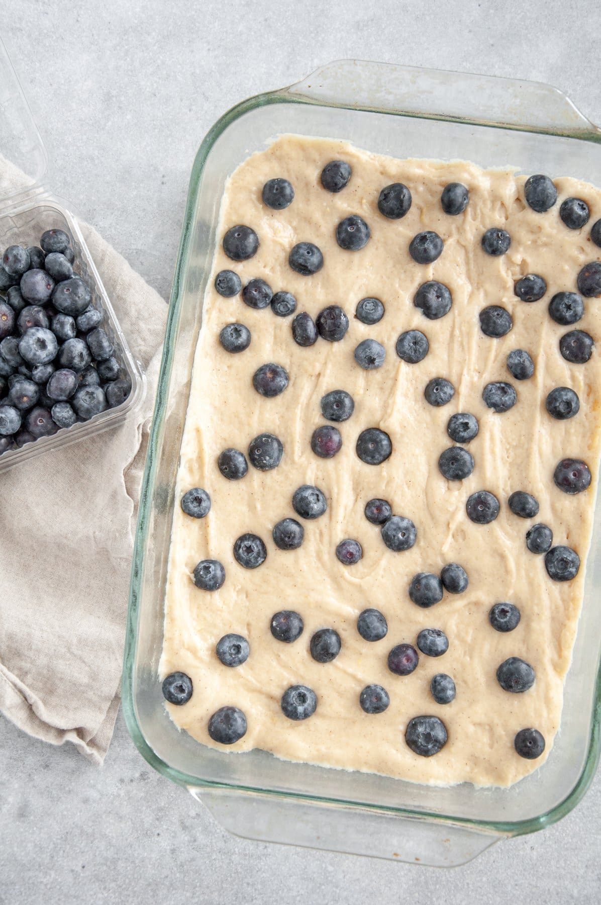 lemon cake batter with blueberries on top of it all in a baking dish