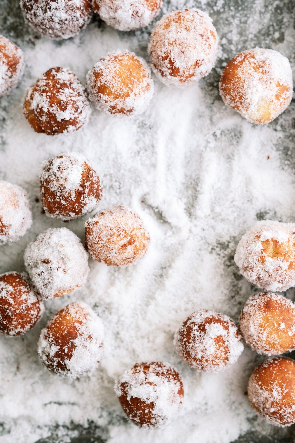 donut holes on a baking sheet being rolled around in sugar