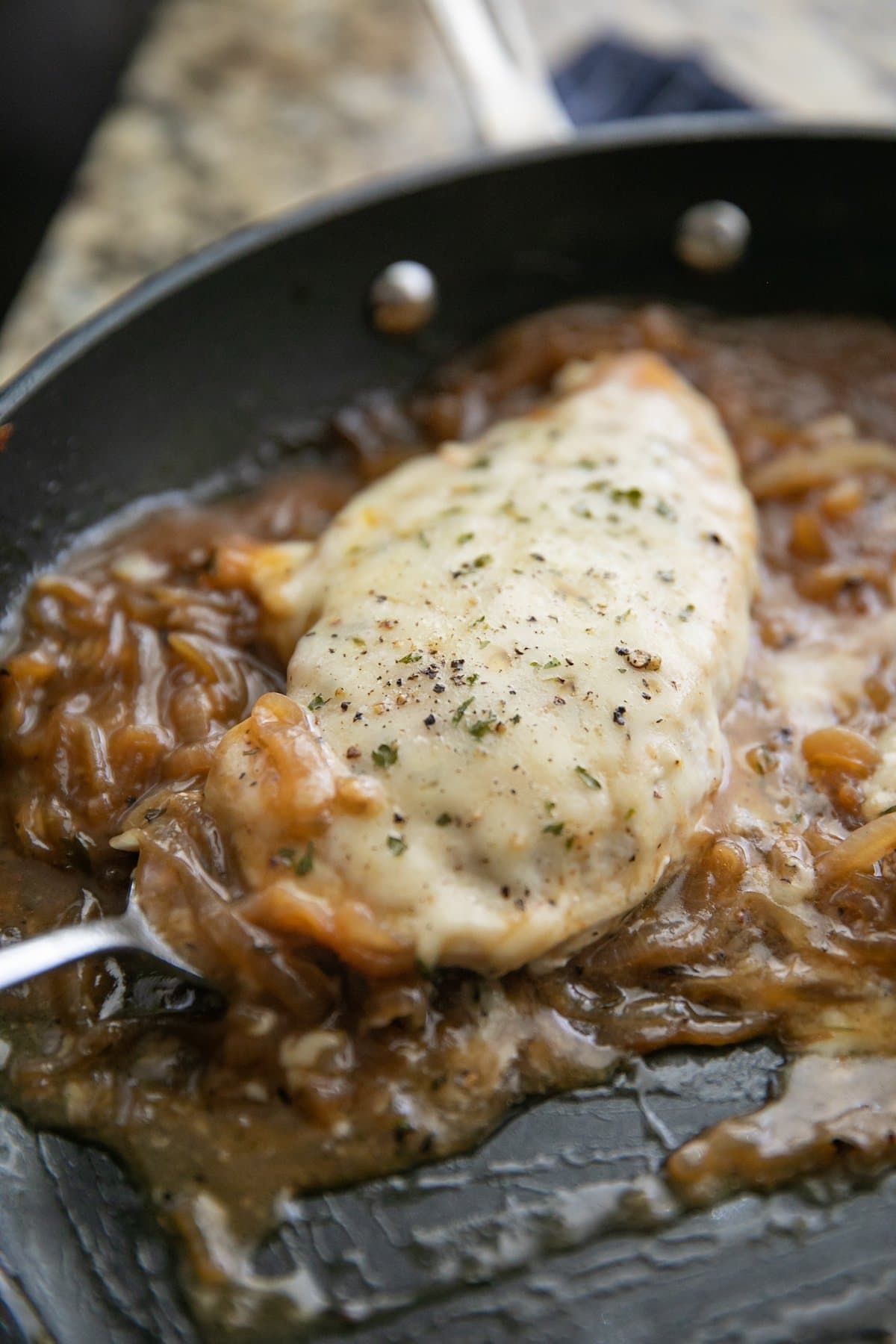 french onion chicken being lifted out of a skillet