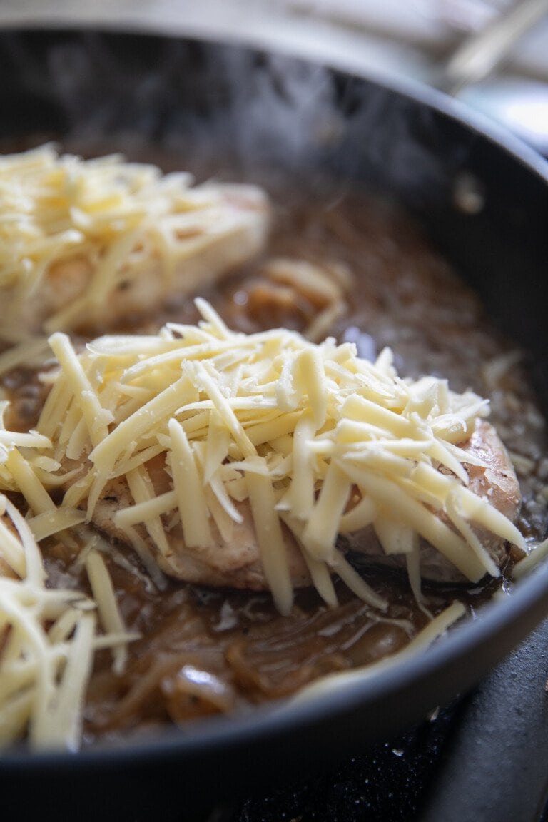 topping chicken with shredded gruyere cheese